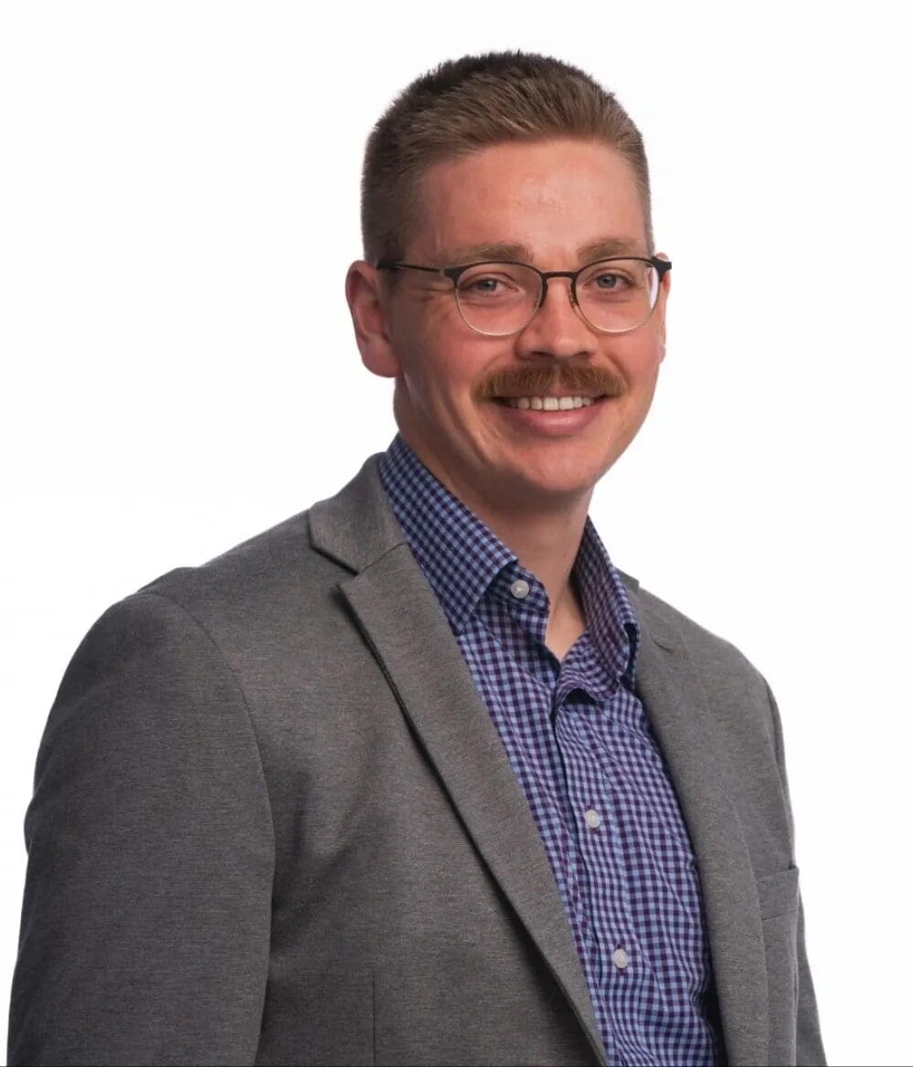 A man with a mustache wearing glasses and a jacket.