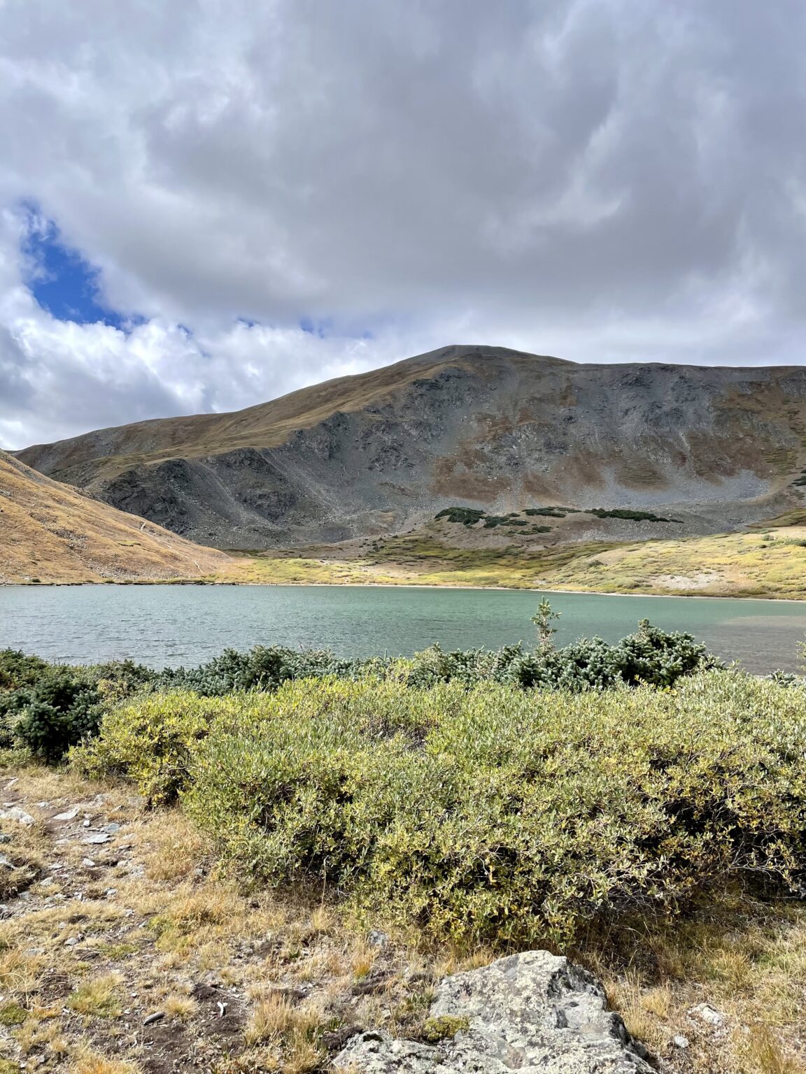 A lake surrounded by green bushes and mountains.