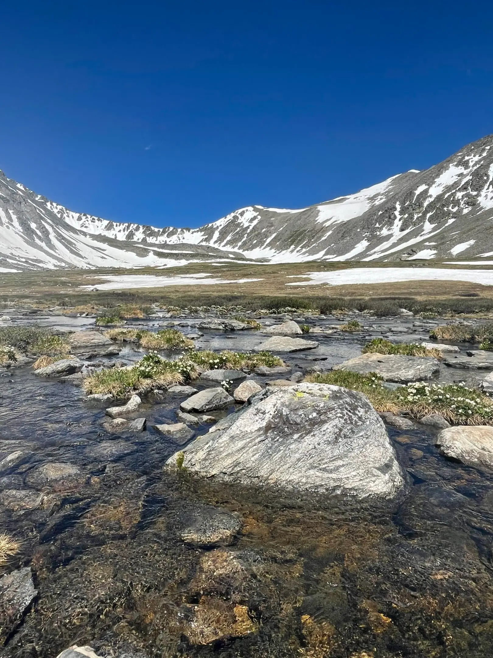 A mountain with snow on top and water in the middle of it.